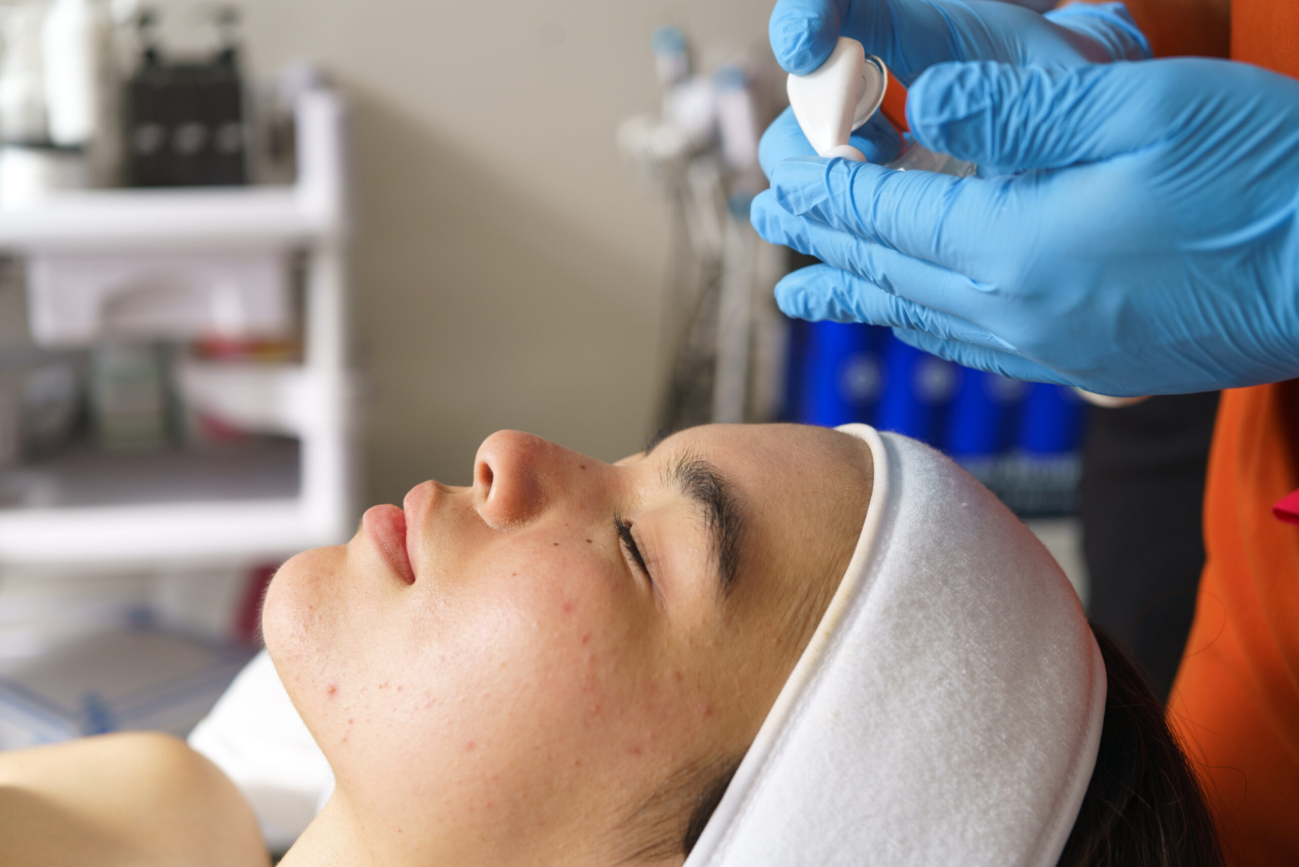 Skincare professional treating acne prone complexion using professional ultrasonic cleansing technique for dermatological improvement